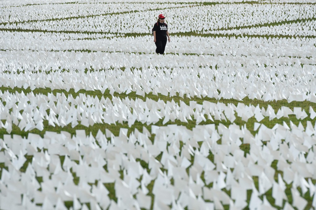 A woman walks through a field of white flags on the Mall near the Washington Monument in Washington, DC. More than 600,000 miniature white flags symbolise the lives lost to Covid-19 in the US. Photo: AFP