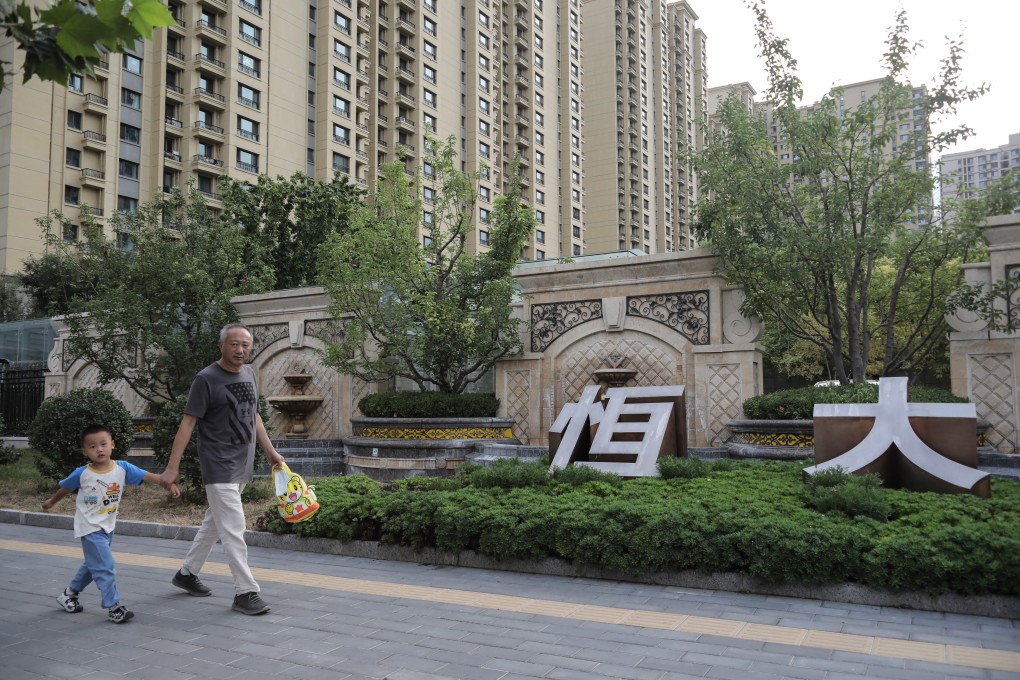 Residents walk near the Evergrande corporate name outside a residential complex in Beijing in September 2021 as the developer’s liquidity crisis infects market sentiment. Photo: EPA-EFE