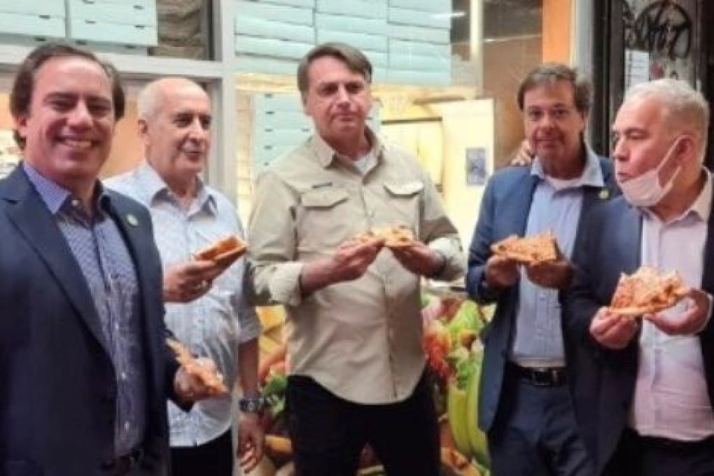 Brazil's President Jair Bolsonaro (centre) eats pizza with members of his delegation in New York on Saturday. Photo: Gilson Machado Neto via Instagram/Reuters