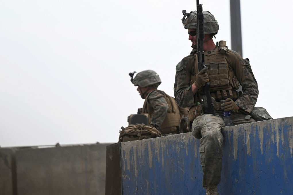 US soldiers sit on a wall as Afghans gather on a roadside near the military part of the airport in Kabul on August 20, 2021. Photo: AFP