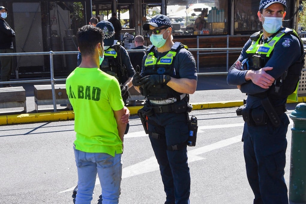 Australian police speak with a man during a patrol to prevent protests by construction workers and demonstrators against Covid-19 regulations in Melbourne on Thursday. Photo: AFP