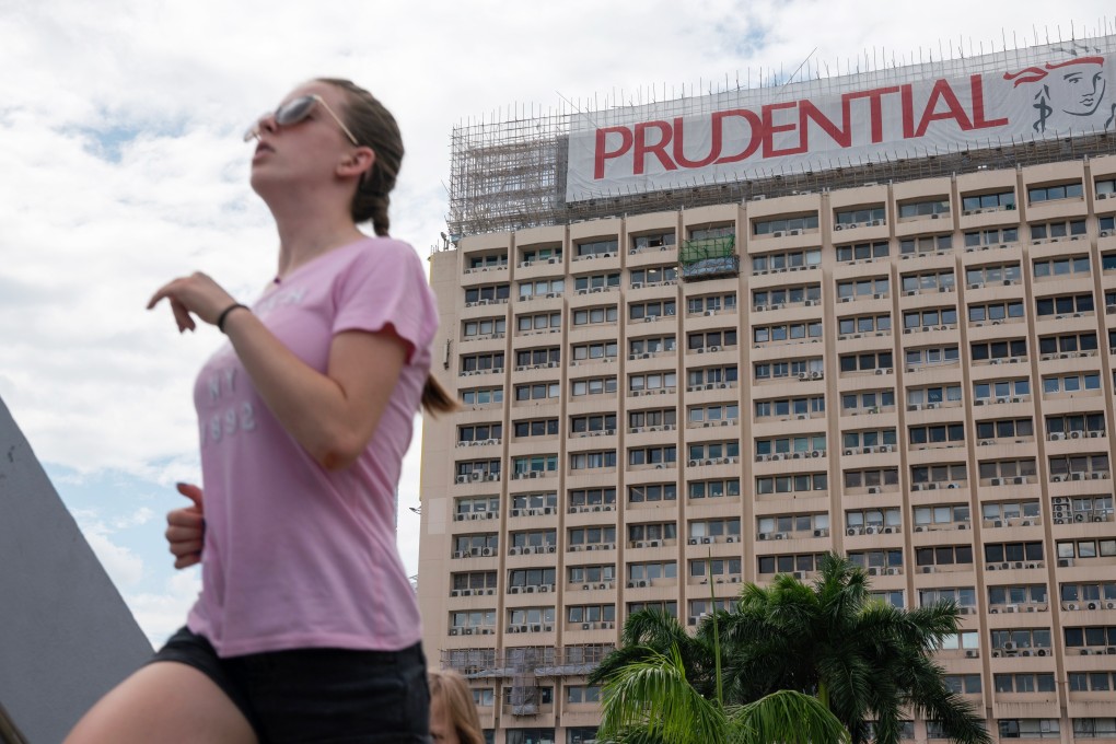 A woman runs past a banner featuring the Prudential logo in Hong Kong. Photo: Bloomberg