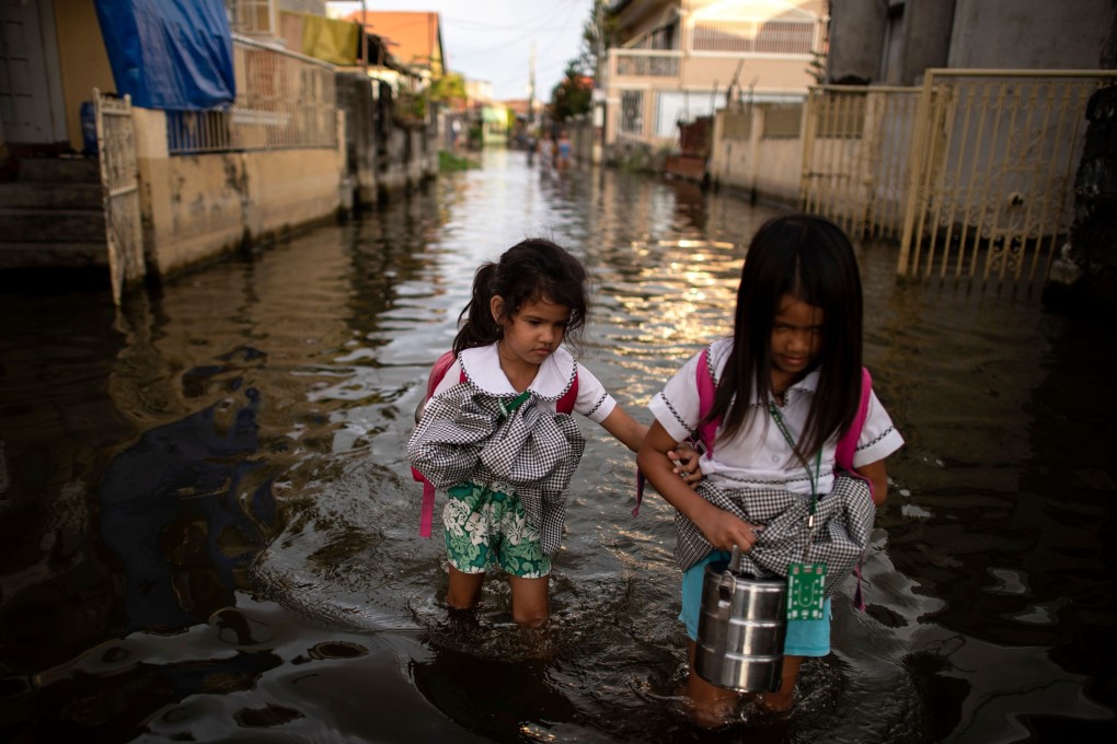 Primary school students wade through floodwaters in Pampanga, Philippines. File photo: AFP