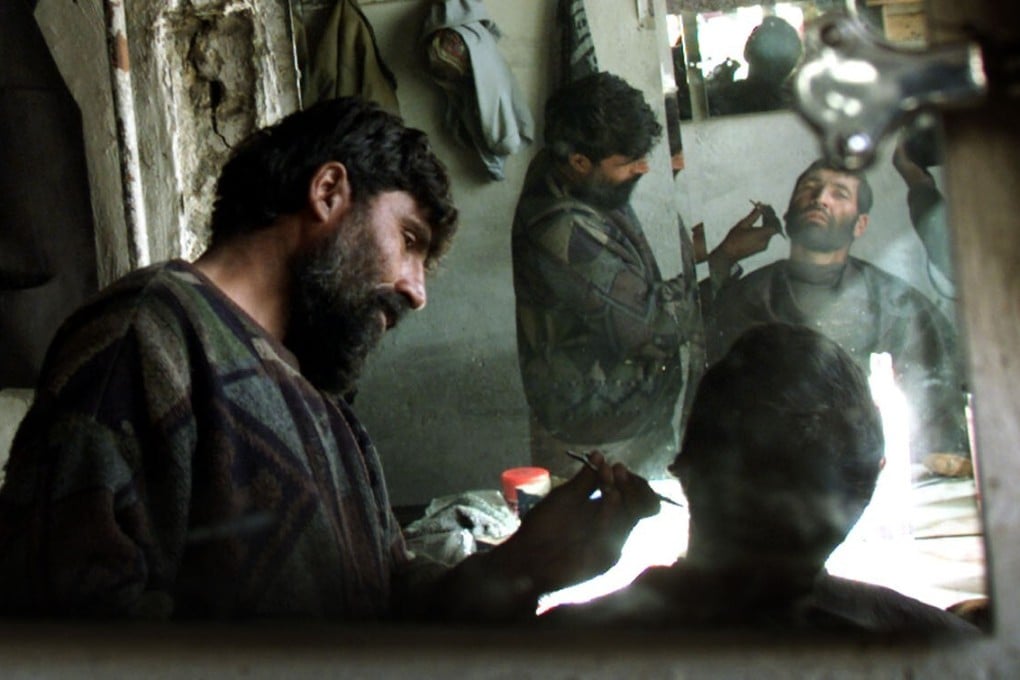 An Afghan man has his beard shaved in a barber shop in Kabul in November 2001. Shaved or cleanly trimmed beards became popular after the Taliban was ousted 20 years ago. Photo: Reuters