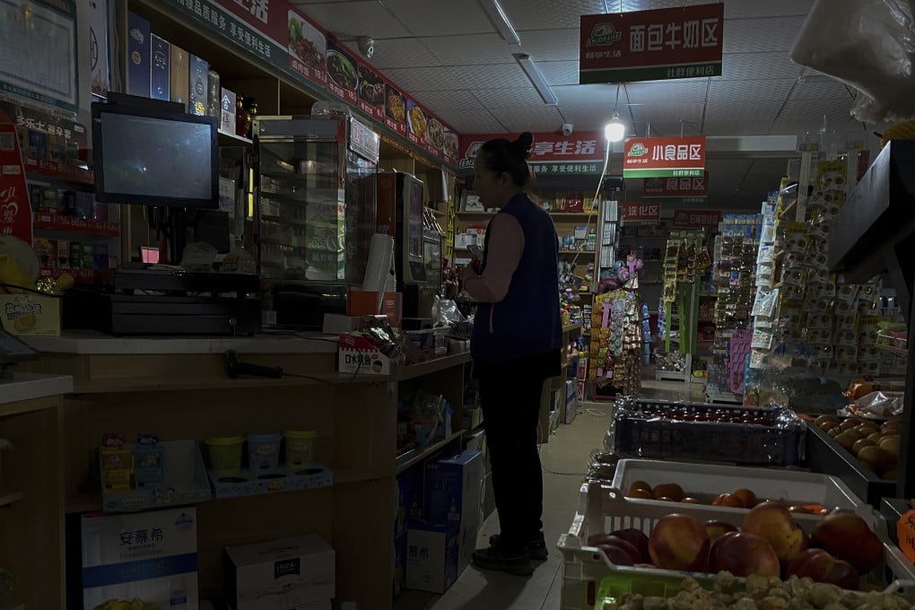 A woman buys groceries from a mini-market using a light bulb powered by a petrol generator during a blackout in Shenyang, Liaoning province, on Wednesday. Photo: AP