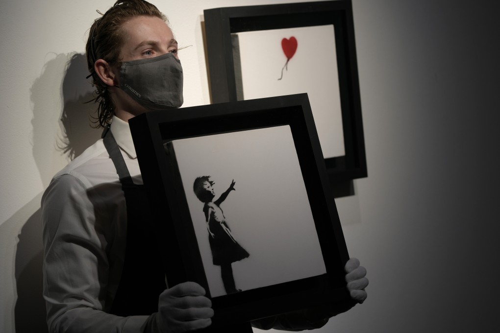 A staff member holds Banksy’s Girl and Balloon (two parts) during a pre-auction press viewing at Christie’s in London on Friday. Photo: AP