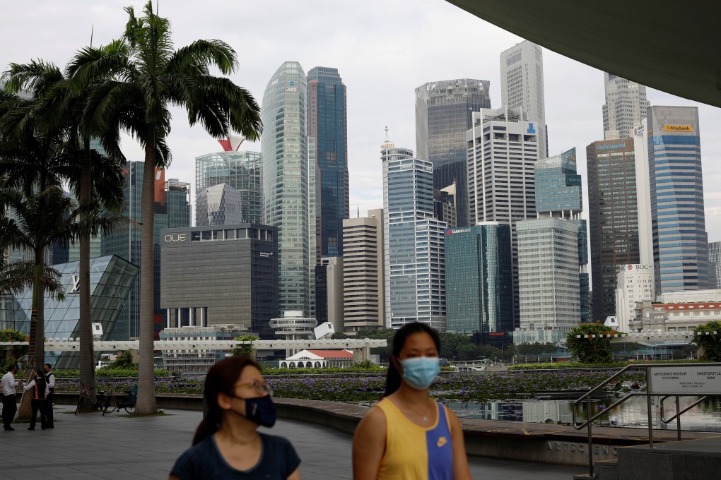 People wearing face masks pass in front of the Singapore central business district. The city state is aiming to open up more travel lanes by the end of the year. Photo: Reuters