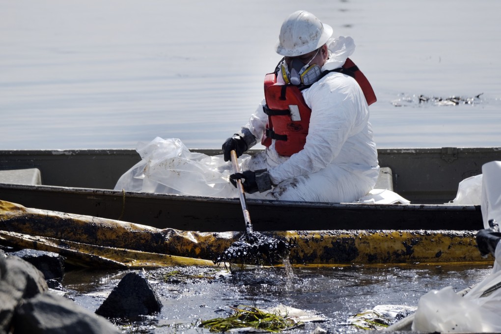A clean-up contractor deploys booms to try to stop further oil crude incursion into wetlands. Photo: AP