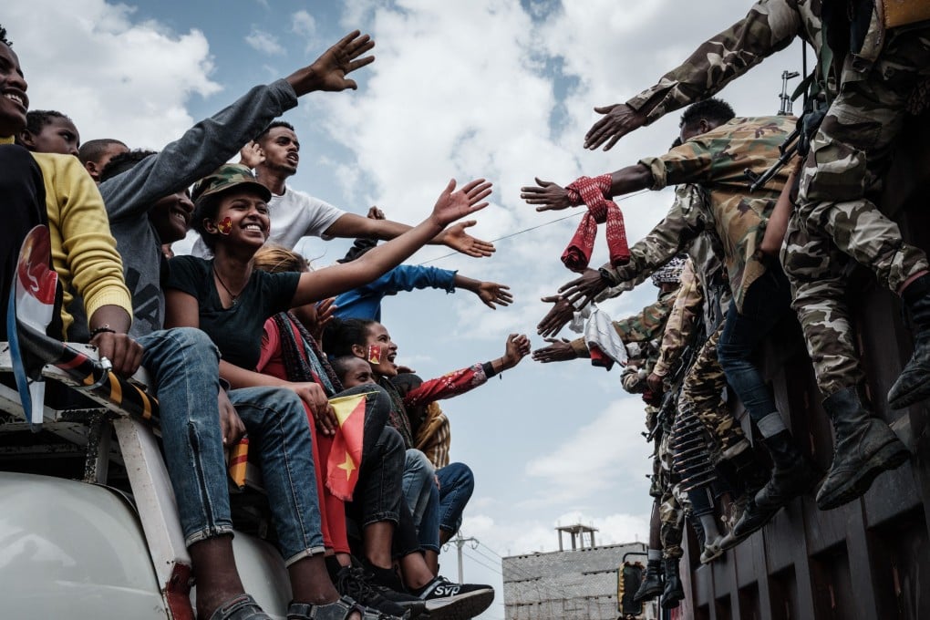 People on a bus try to touch hands with Tigray Defence Force soldiers as they arrive in Mekele, capital of Ethiopia’s war-hit region, in June. It is one of three African nations seeking debt relief under the G20’s new framework. Photo: AFP