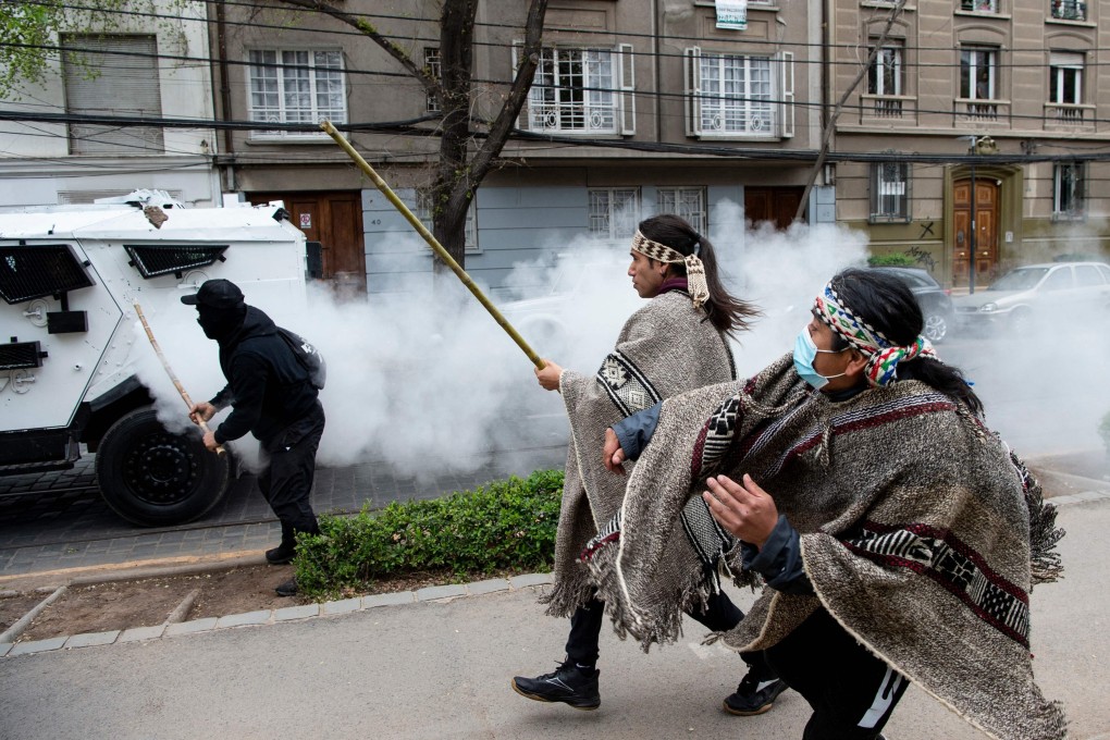 Mapuche indigenous men clash with riot police during a protest in downtown Santiago, Chile on Sunday. Photo: AFP
