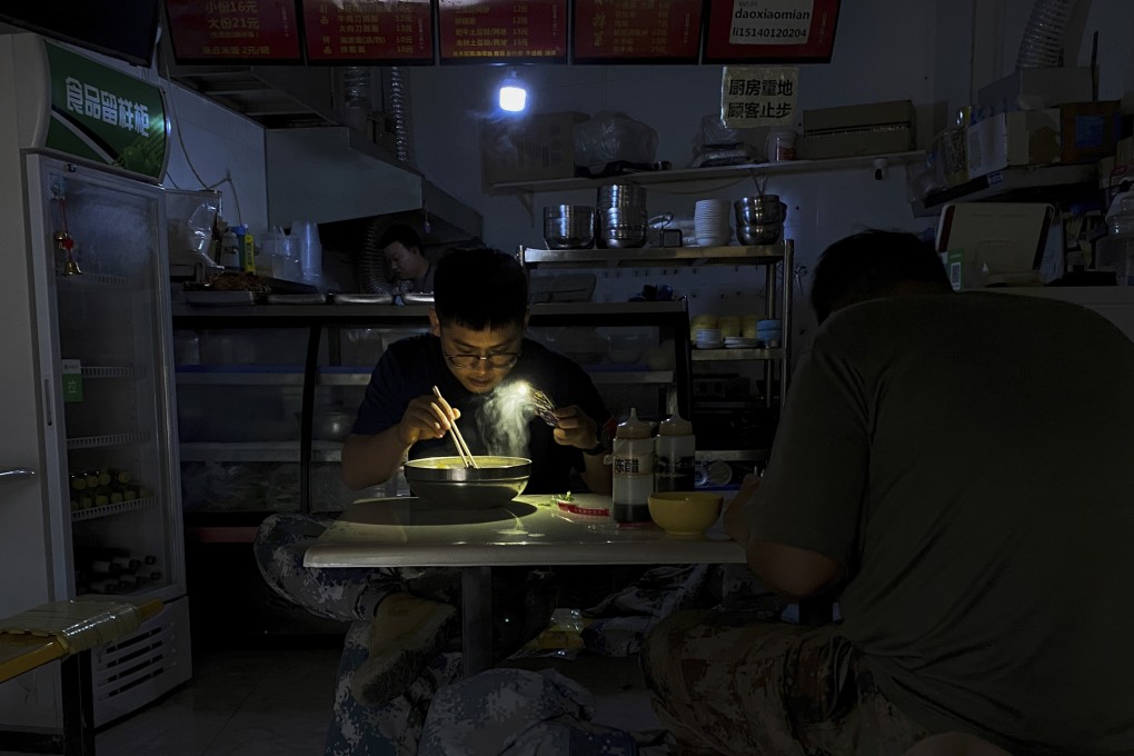 A man eats noodles by the light of his cellphone during a recent blackout in Shenyang, Liaoning province. Photo: AP