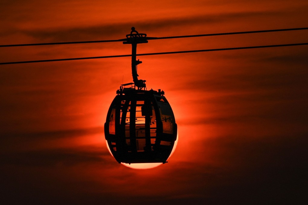 The sun sets behind a passing cable car cabin in Singapore. Photo: AFP