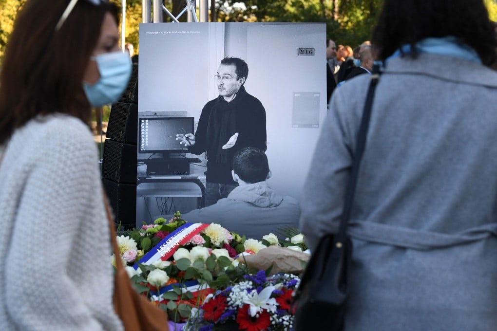 Members of the public stand in front of a photograph of teacher Samuel Paty at a tribute ceremony in Paris, one year after he was beheaded by an extremist after showing his class cartoons of the Muslim Prophet Mohammed. Photo: AFP