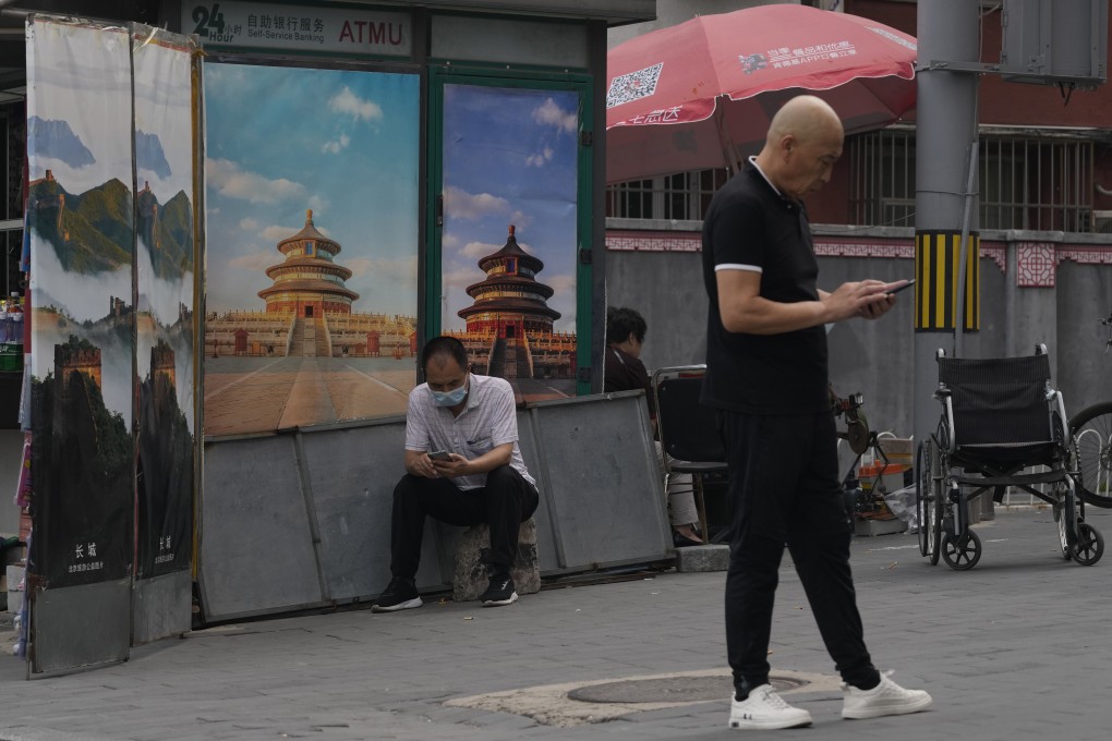 Chinese men use their smartphones on the streets of Beijing on August 22, 2021. Three months into a targeted campaign against the internet industry, China’s Ministry of Industry and Information Technology said scrutiny of the industry will deepen. Photo: AP
