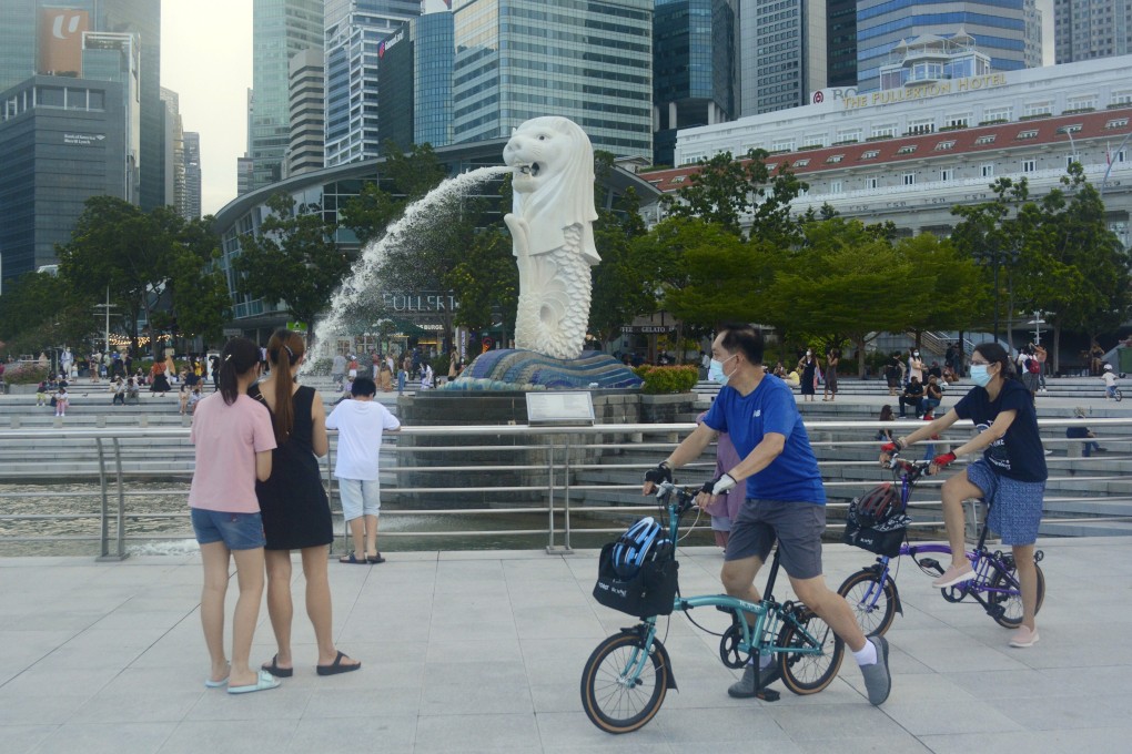 Cyclists wearing faces masks pass near the Merlion statue in Singapore. Photo: AP
