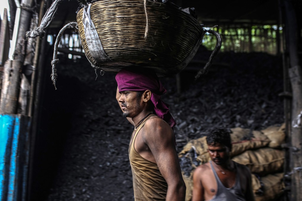A worker carries a basket of charcoal at wholesale market in Mumbai, India. India, the third-biggest emitter of greenhouse gases, still relies on coal for about 70 per cent of electricity generation. Photo: Bloomberg
