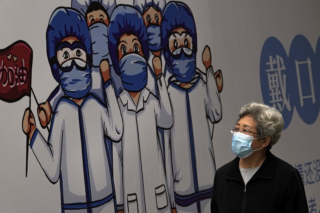 A woman walks past a billboard depicting medical workers in Beijing. Photo: AP