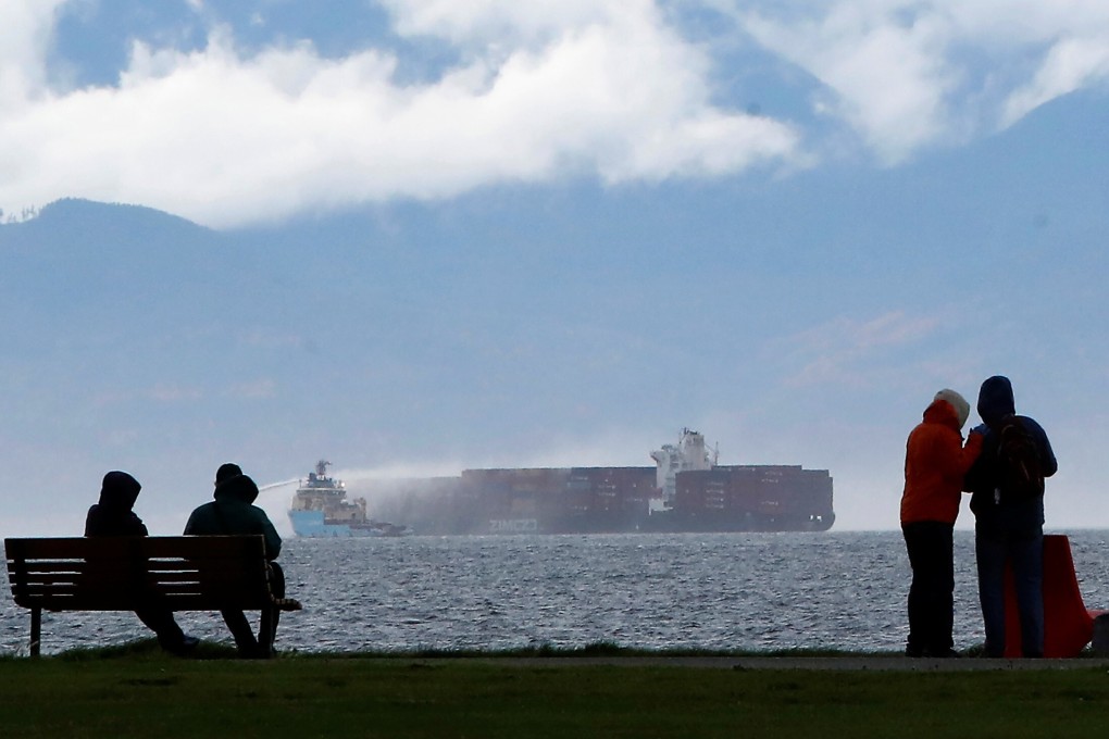 People watch from Clover Point Park in Victoria, British Columbia, as salvage tug boats spray water onto the container ship Zim Kingston. Photo: Reuters