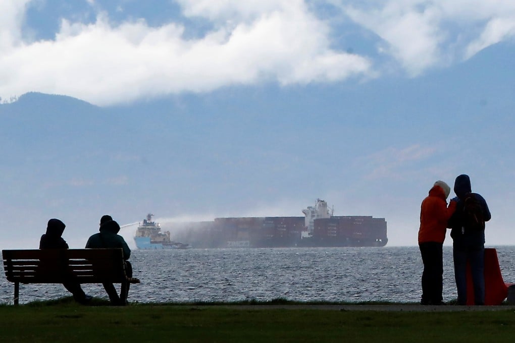People watch from Clover Point Park in Victoria, British Columbia, as salvage tug boats spray water onto the container ship Zim Kingston. Photo: Reuters