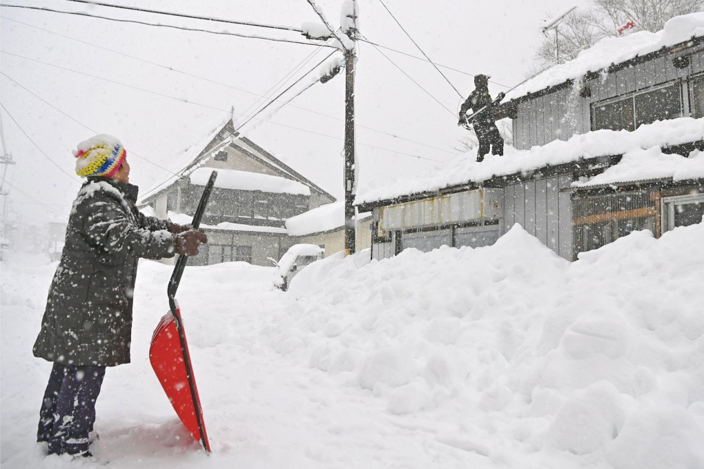 People work to remove snow from the roof of a house in eastern Japan last winter. Photo: Kyodo