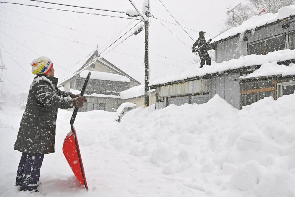 People work to remove snow from the roof of a house in eastern Japan last winter. Photo: Kyodo
