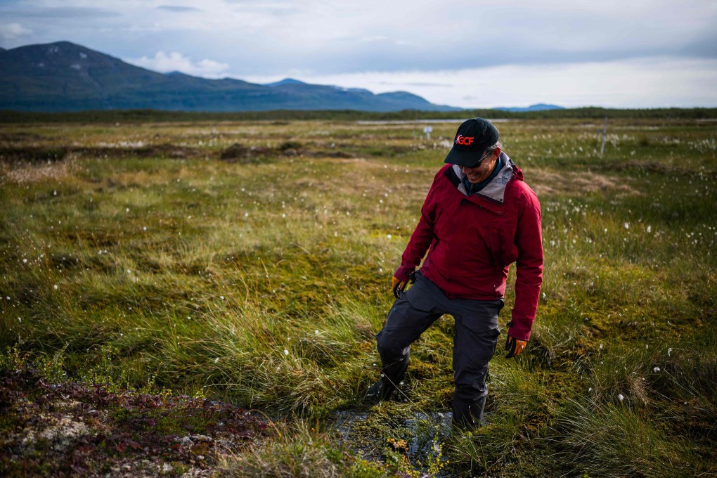 Bubbles of methane rise to the surface of the water at Stordalen mire in northern Sweden, as Keith Larson, head of the Abisko Scientific Research Station, demonstrates the effects of the melting permafrost beneath the marshy land on August 24, 2021, near the village of Abisko, in Norrbotten County, Sweden. – In the Arctic in Sweden's far north, global warming is happening three times faster than in the rest of the world. Storflaket and the nearby Stordalen sites are key centres of research in Europe into the effects of climate change on permafrost. The methane is released as the permafrost melts. (Photo by Jonathan NACKSTRAND / AFP)