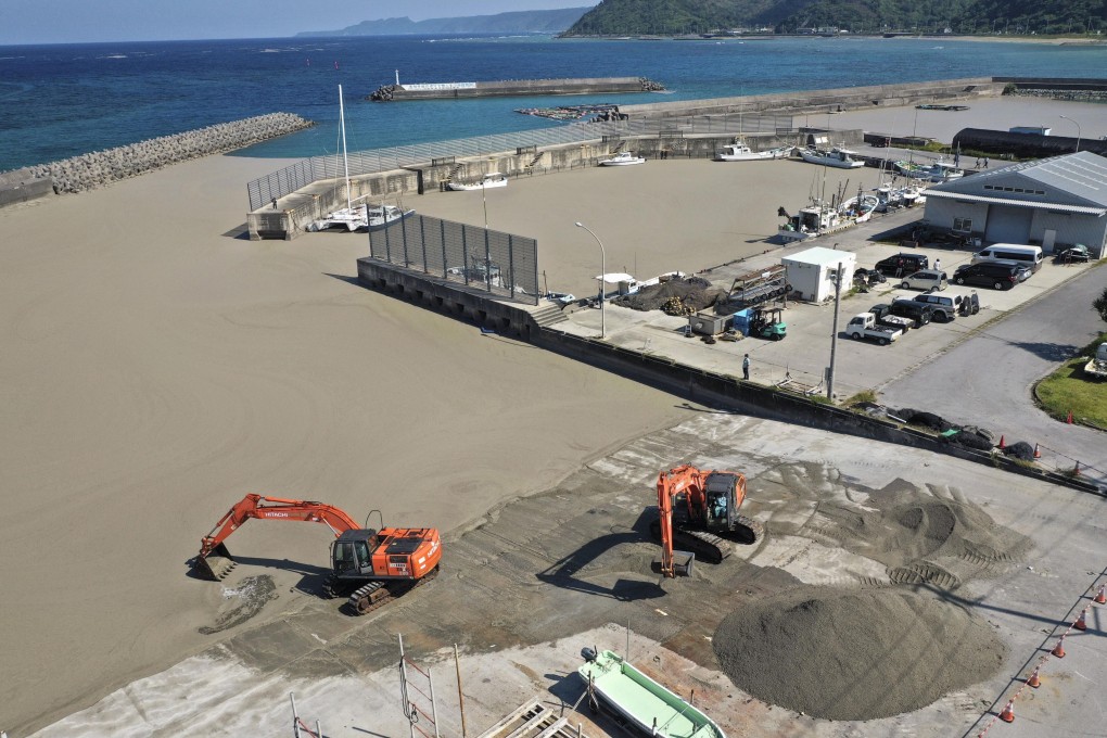 Clean-up work at a port in Kunigami in the southern Japan island prefecture of Okinawa to remove a massive amount of pumice stones that drifted ashore following an underwater volcanic eruption earlier this year. Photo: Kyodo