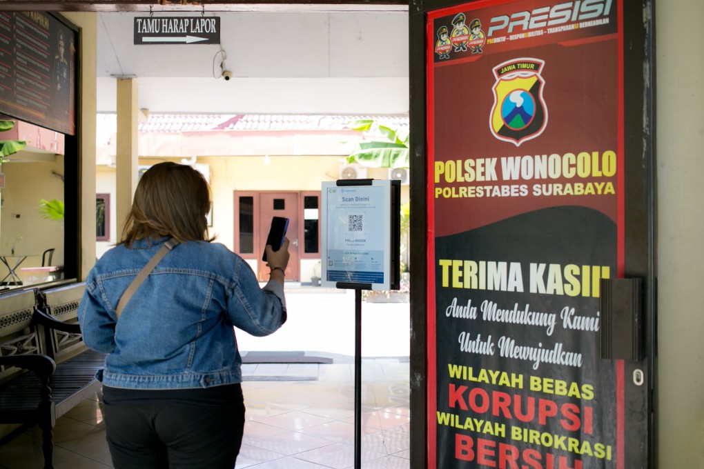 A visitor to the Wonocolo Police Station in Surabaya, Indonesia, scans their vaccine information before entering. Photo: Ivan Darski