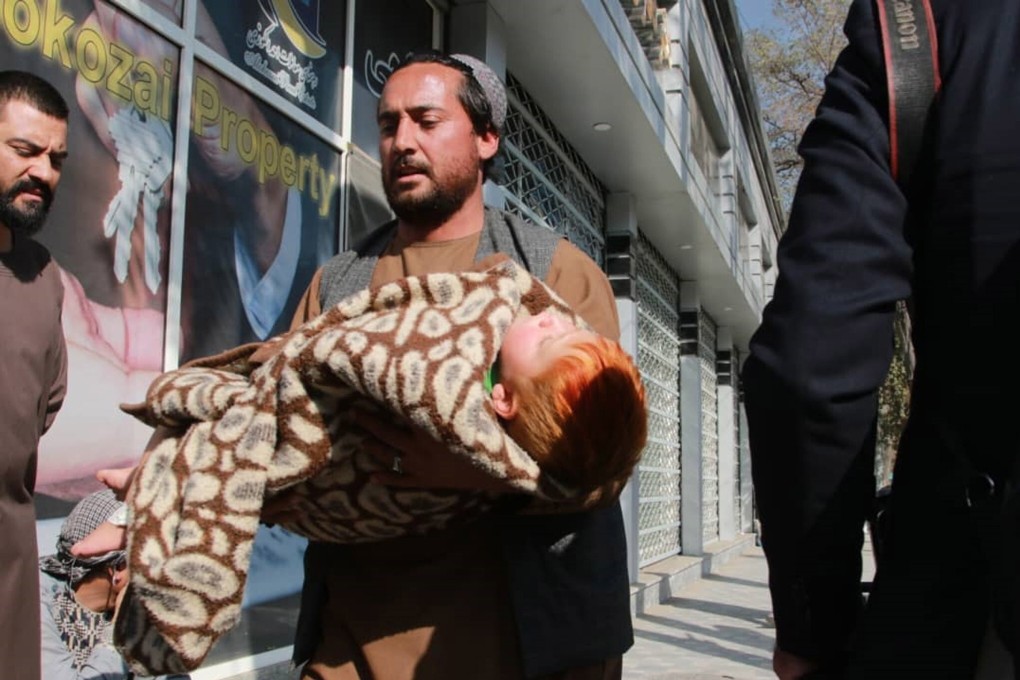 A man carrying a child flees the scene of bomb blasts targeting a military hospital in Kabul, Afghanistan, on Tuesday. Photo: EPA