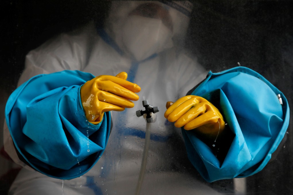 A health worker wearing personal protective equipment seen sanitising his gloves amid the pandemic. Photo: Reuters