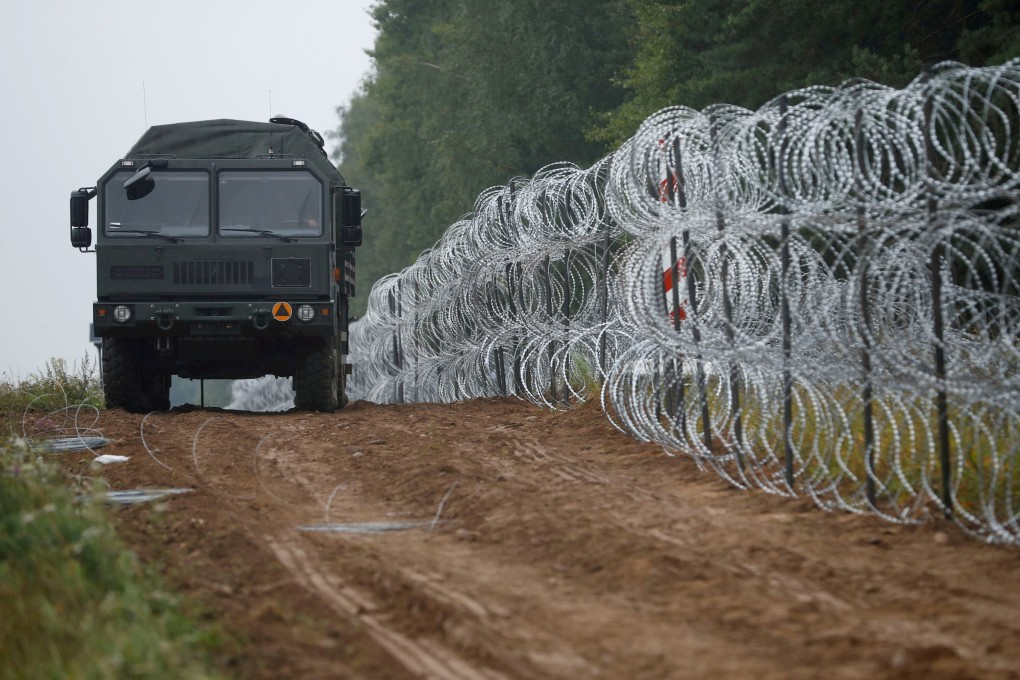 An army vehicle patrols next to a fence built by Polish soldiers on the border with Belarus. Photo: Reuters