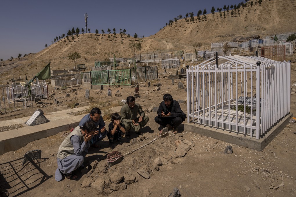 The Ahmadi family pray at the cemetery next to graves of family members killed by a US drone strike. Photo: AP