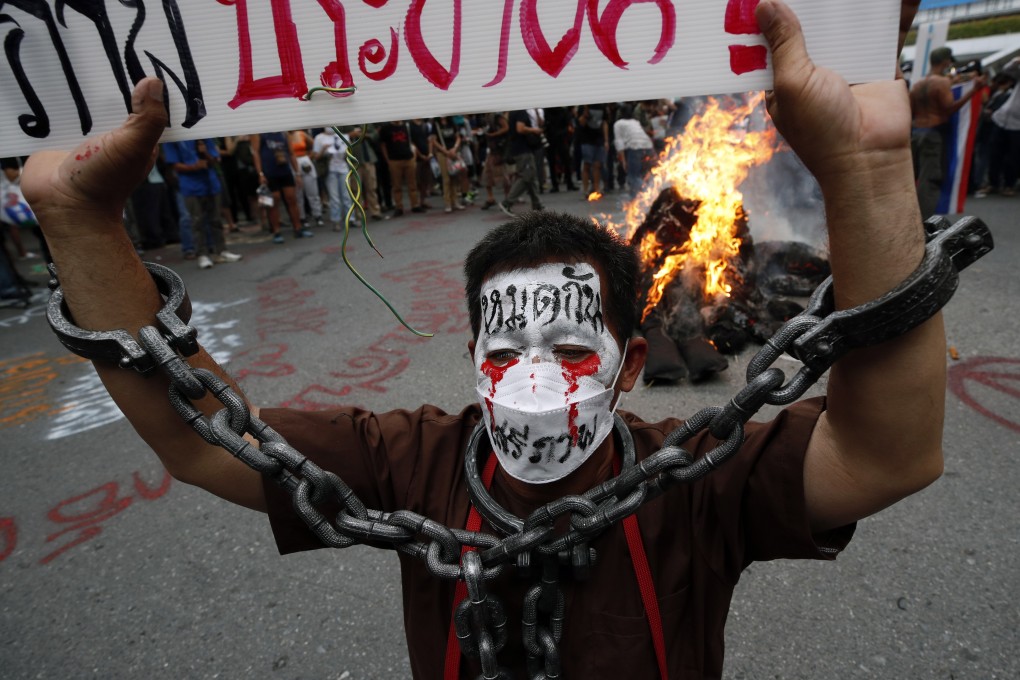 A demonstrator stands next to a burning effigies during a street protest in Bangkok. Photo: EPA-EFE