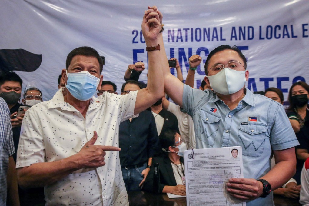 Philippine President Rodrigo Duterte raises the hand of Senator Christopher “Bong” Go after he filed his candidacy for president in the 2022 elections. Photo: AFP