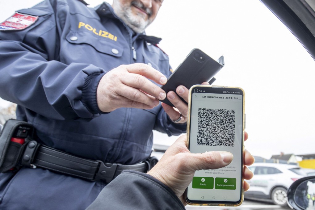 An Austrian police officer checks a driver's digital vaccination certificate. Photo: AFP