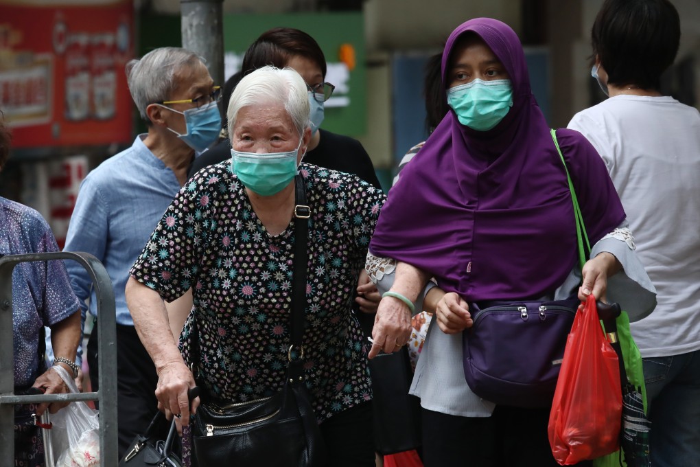 A domestic worker crosses the road with an elderly woman in Sai Ying Pun, Hong Kong. Photo: SCMP / Jonathan Wong