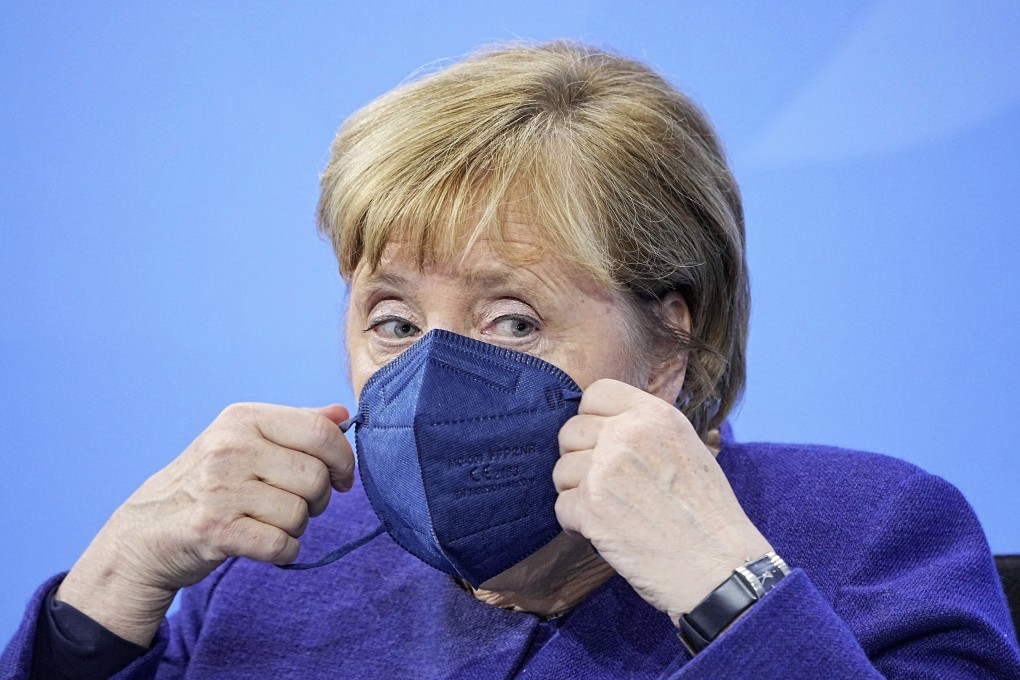 German Chancellor Angela Merkel puts on a face mask as she attends a news conference in Berlin on Thursday. Photo: AP