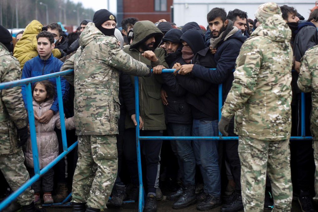 Belarusian servicemen stand next to a barrier as migrants jostle to receive food outside the transport and logistics centre near the Belarusian-Polish border in the Grodno region, Belarus on Sunday. Photo: Reuters