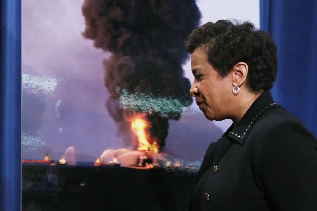 U.S. Attorney General Loretta E. Lynch walks past a photograph of the April 2010 Deepwarter Horizon platform in flames after announcing the resolution of federal and state claims against BP . Photo: AFP