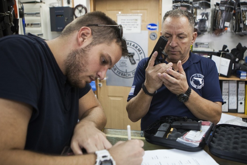 An Israeli man buys a gun in a weapons shop near the West Bank Jewish settlement of Givat Zeev on Sunday. Photo: AP