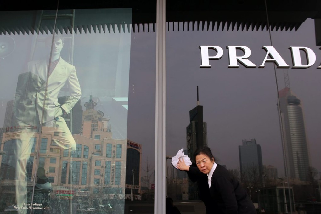A cleaner wipes the glass outside a store of luxury brand Prada in Qingdao city, Shandong province. China now has a middle-class population of 109 million. Photo: EPA