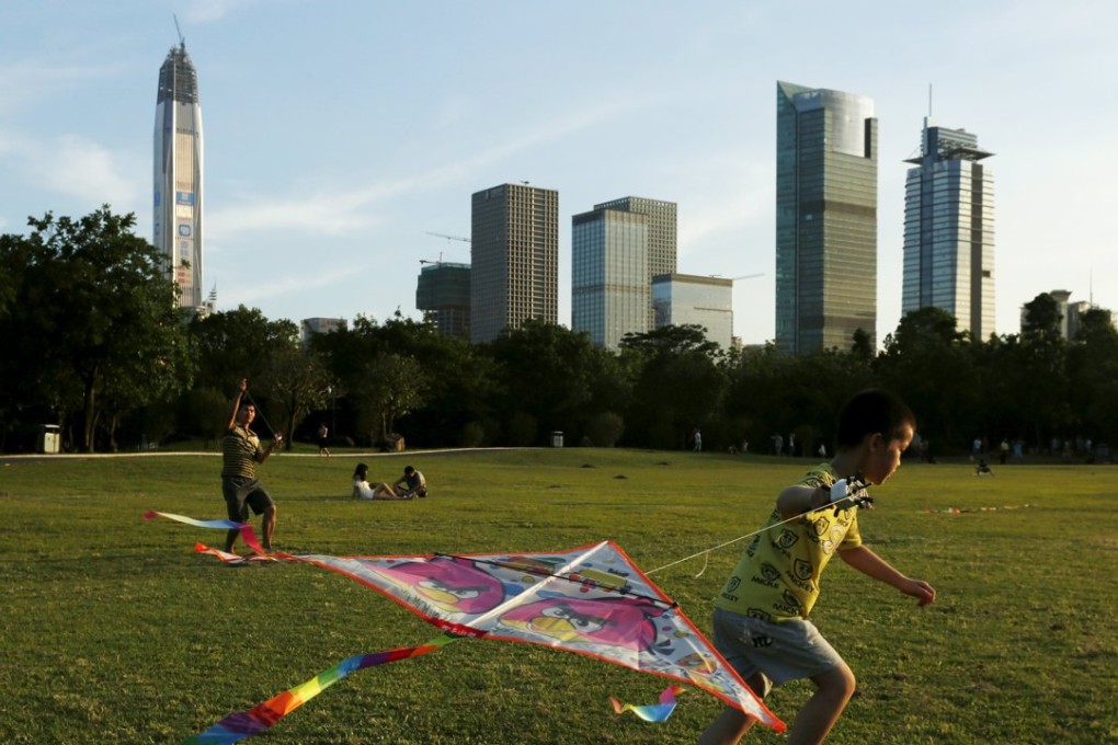 Children fly kites at a park in front of commercial towers, including the 115-storey Ping An International Finance Center, which is under construction in Shenzhen. Photo: Reuters