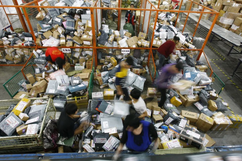 Workers sort out parcels beside a conveyor belt in a YTO Express transfer centre in Shanghai. Photo: Xinhua