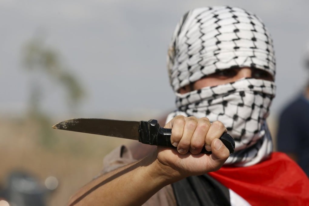 A masked Palestinian protester holds a knife during a protest near the Israeli border fence in northeast Gaza. Photo: Reuters