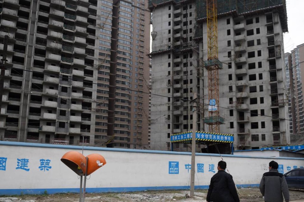 Two men walk past a construction site for apartment buildings in Beijing as internet-based rivals pose an increasing challenge to traditional property companies in the market. Photo: AFP