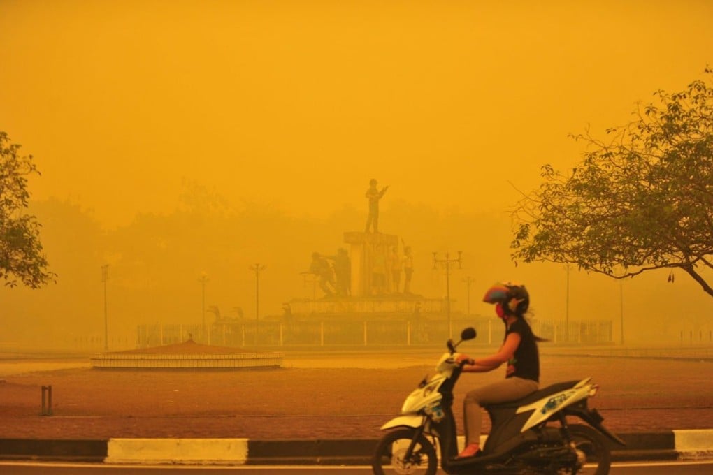 An Indonesian woman rides a motorbike amid thick yellow haze in Palangkaraya, Central Kalimantan province. Photo: EPA
