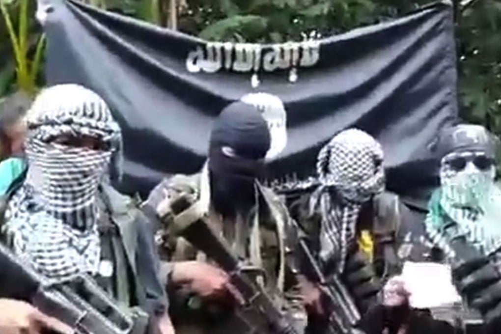 Gunmen stand behind three foreign men (not pictured) and a Filipina (not pictured) who were kidnapped last month in the southern Philippines. Photo: AFP