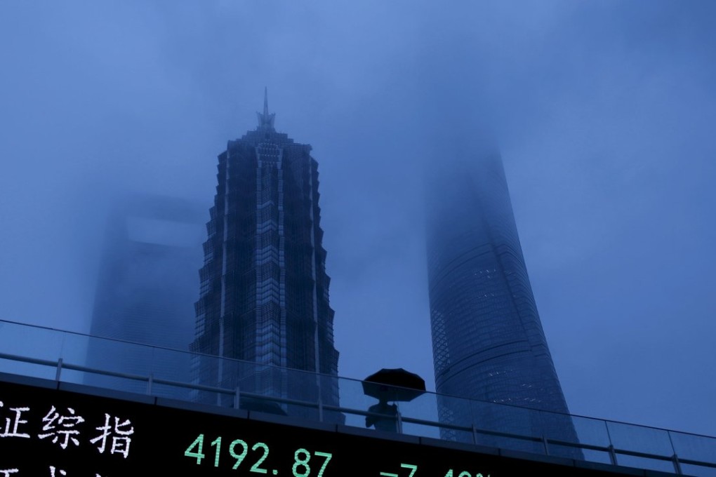 A man walks past an electronic board showing the benchmark Shanghai and Shenzhen stock indices on a hazy, gloomy day in Shanghai. Photo: Reuters