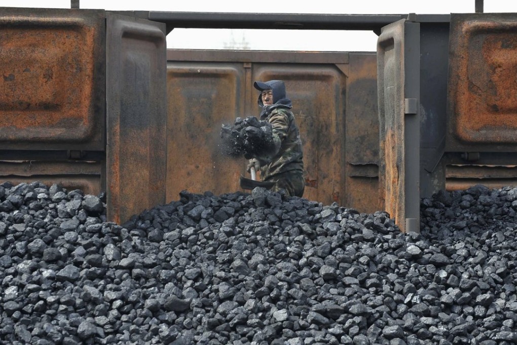 A worker unloads coal at a storage site along a railway line in Shenyang, Liaoning province. Photo: Reuters