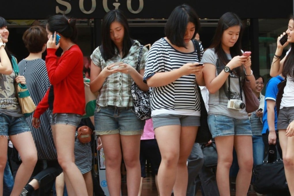 Girls play with smartphones in Causeway Bay, Hong Kong. Photo: SCMP Pictures